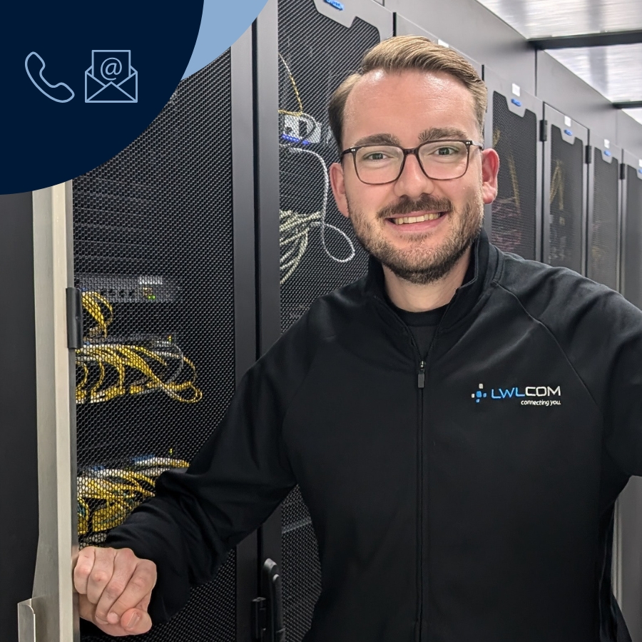 Vertriebsmitarbeiter Keno Rademaker trägt schwarze Jacke mit LWLcom-Logo, steht im Rechenzentrum vor Serverschränken mit Netzwerkkabeln.